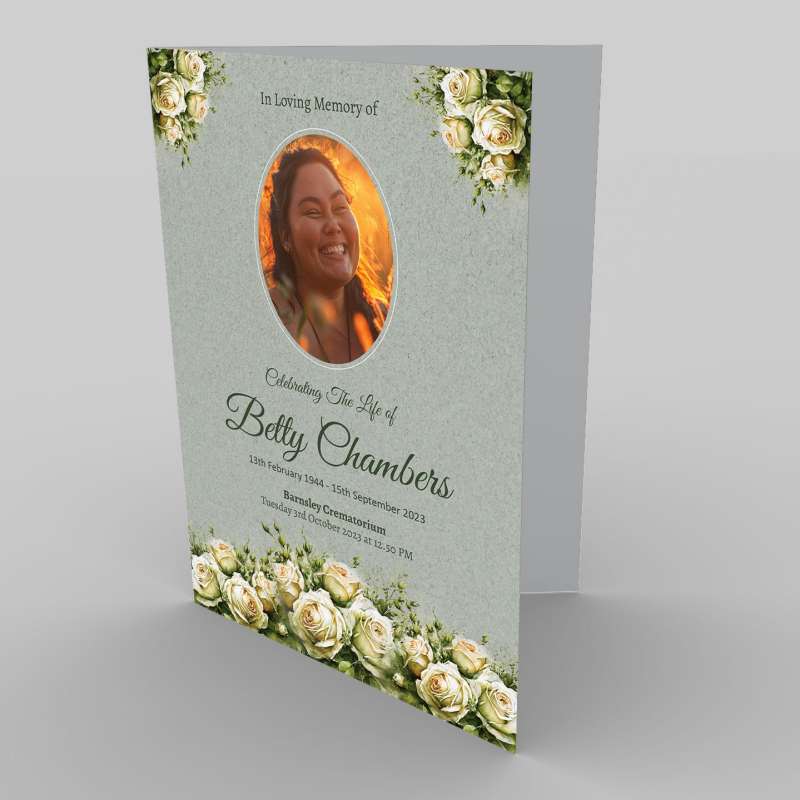 A memorial card featuring a tribute to Betty Chambers, with her photo surrounded by 2.7.2 White Rose and Green flowers, commemorating her life from 1944-2023.